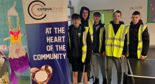 Four boys in high-vis jackets with a poster advertising Corpus Christi Youth Centre