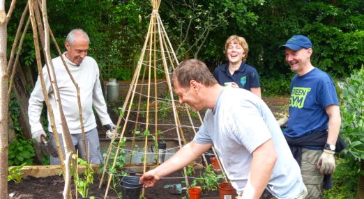 Photograph of four people gardening and smiling