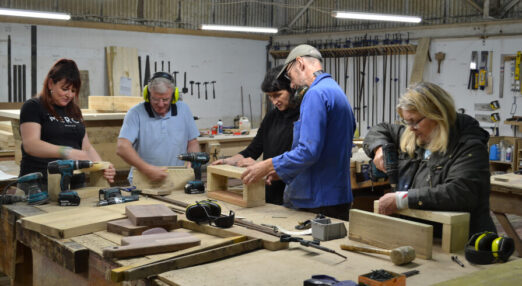 Photograph of 5 people in a workshop doing woodwork